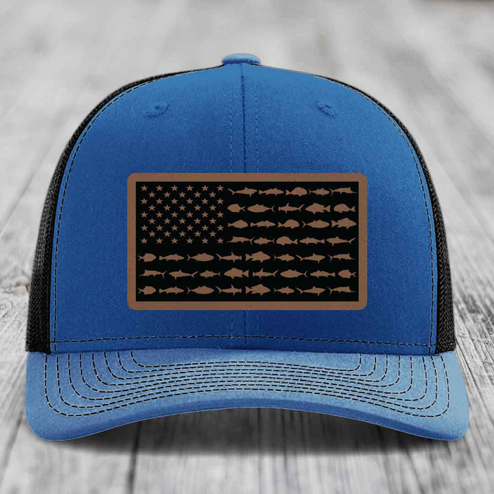 Blue trucker hat with a brown leather patch featuring an American flag design made of fish silhouettes.