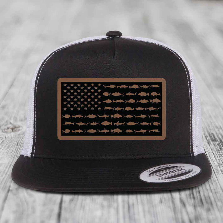 Black and white trucker hat with a brown leather patch featuring an American flag design made of saltwater fish silhouettes.