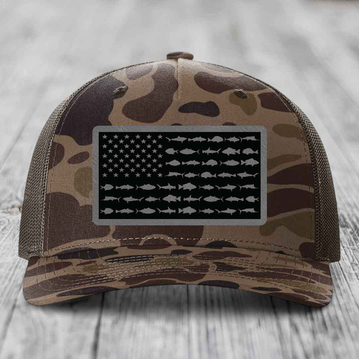 Camouflage trucker hat with American flag patch featuring fish silhouettes instead of stars and stripes.