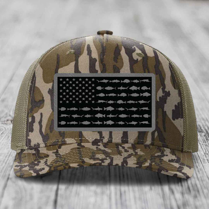 Camouflage trucker hat with American flag patch featuring fish silhouettes instead of stars and stripes.