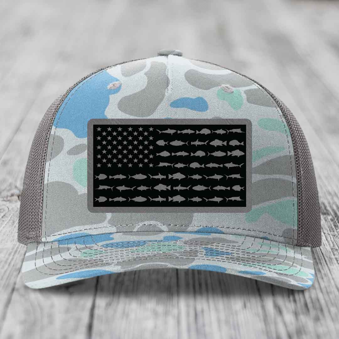 Camouflage trucker hat with American flag patch featuring fish silhouettes instead of stars and stripes.