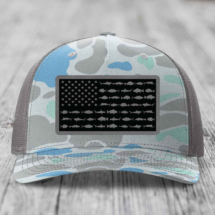 Camouflage trucker hat with American flag patch featuring fish silhouettes instead of stars and stripes.