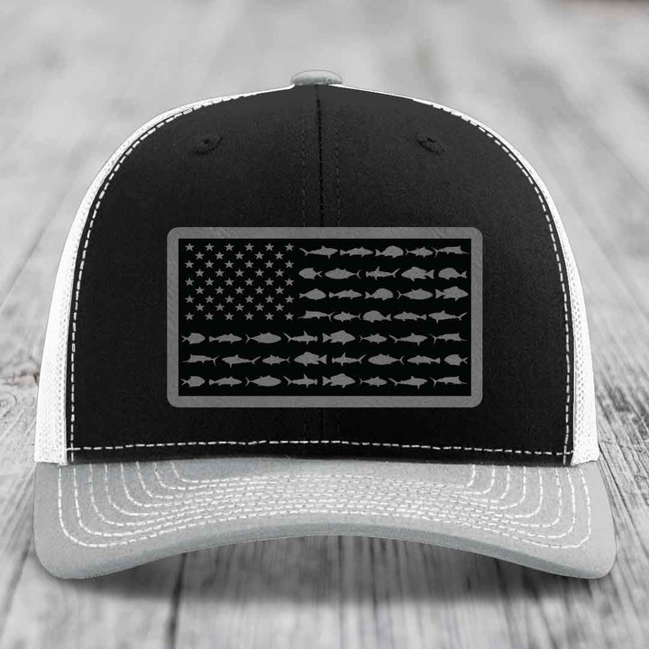 Black and white trucker hat with American flag patch made of saltwater fish silhouettes.