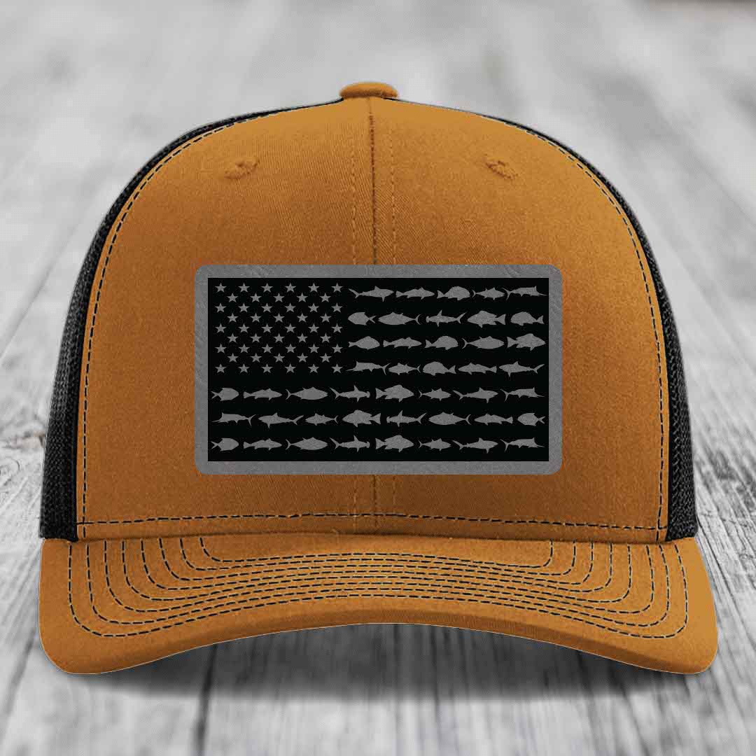 Tan trucker hat with black mesh back and gray American flag patch featuring fish silhouettes instead of stars and stripes.