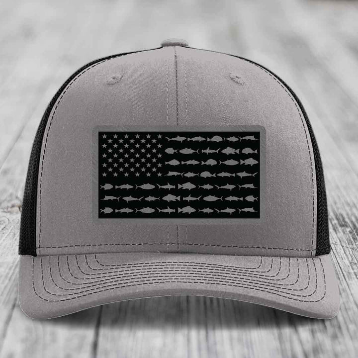 Grey trucker hat with black American flag patch featuring fish silhouettes instead of stars and stripes.