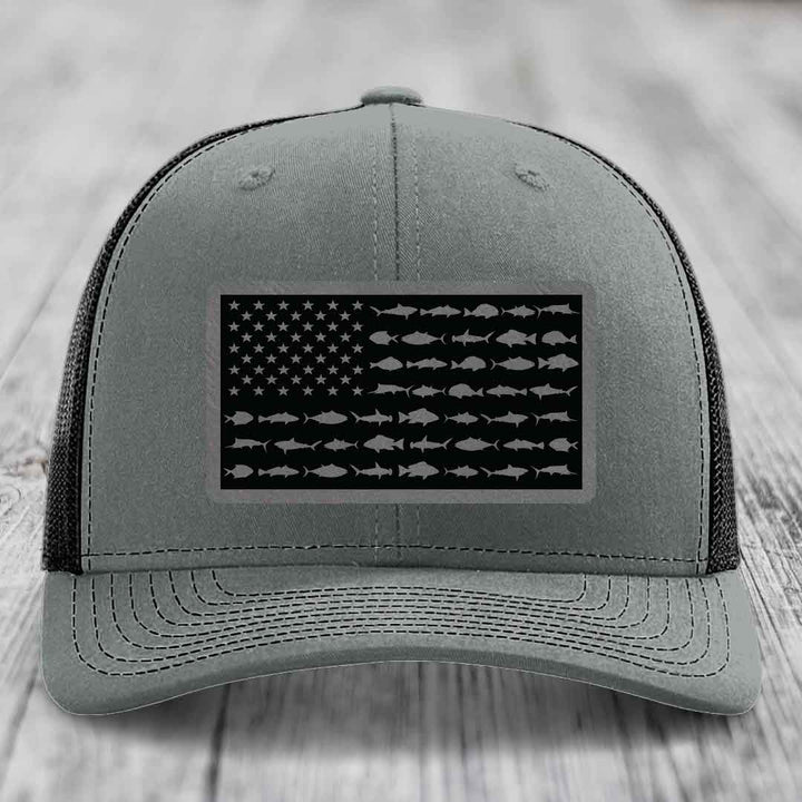 Grey trucker hat with black American flag patch featuring fish silhouettes instead of stars and stripes.