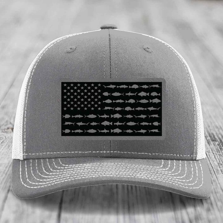 Grey trucker hat with white stitching and a black American flag patch featuring fish silhouettes instead of stripes.