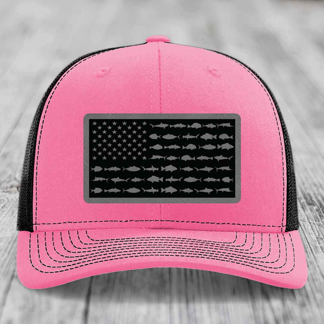 Pink trucker hat with black mesh back and a rectangular patch featuring an American flag design made of fish silhouettes.