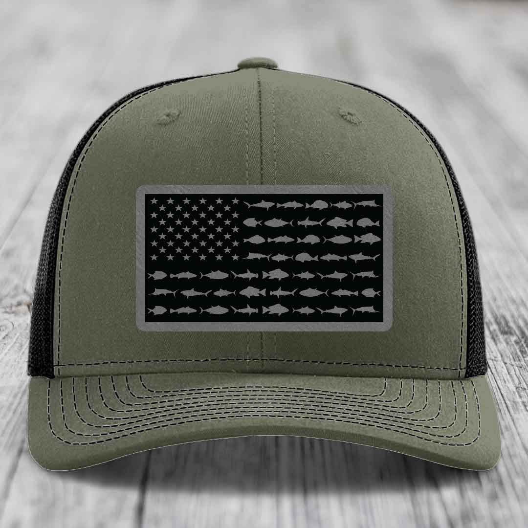 Olive green trucker hat with black American flag patch featuring saltwater fish silhouettes instead of stars and stripes.