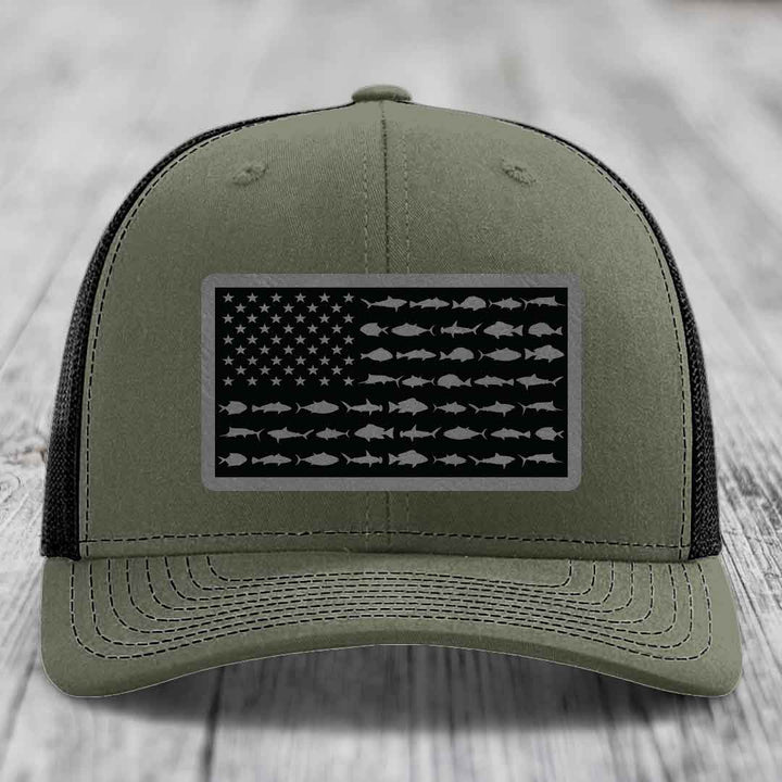 Olive green trucker hat with black American flag patch featuring saltwater fish silhouettes instead of stars and stripes.