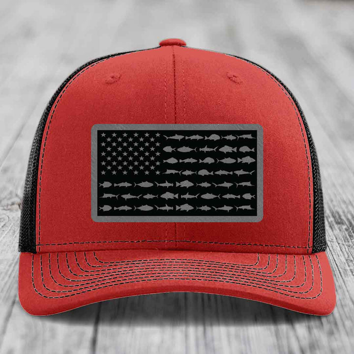 Red and black trucker hat with American flag patch featuring fish silhouettes instead of stars and stripes.