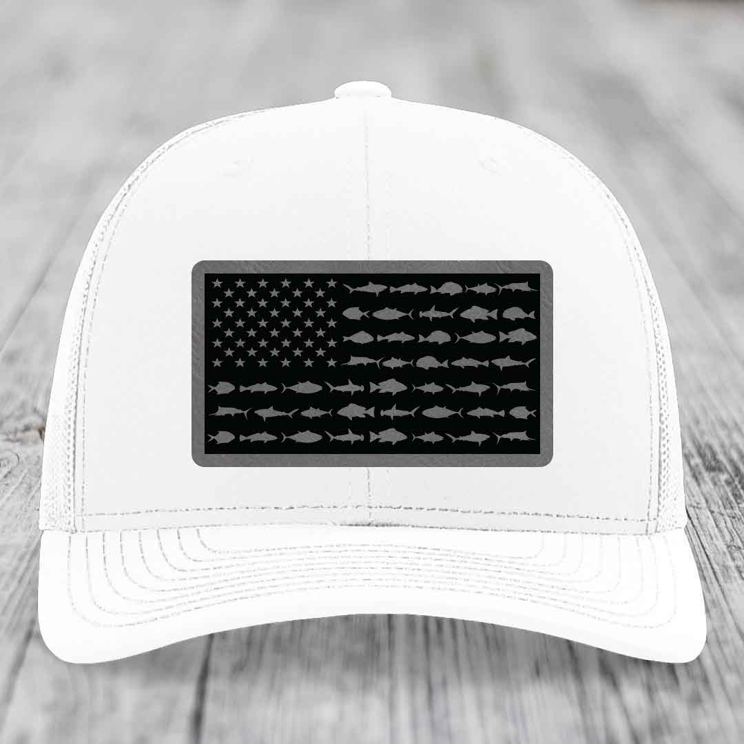 White trucker hat with black leather patch featuring American flag design made of fish silhouettes.
