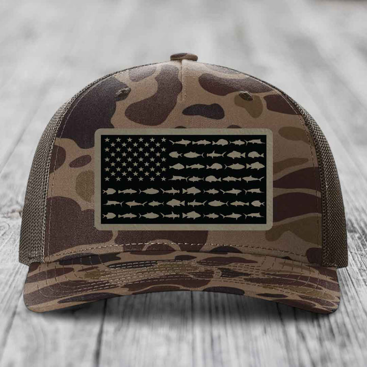 Camouflage trucker hat with American flag patch featuring fish silhouettes instead of stripes.