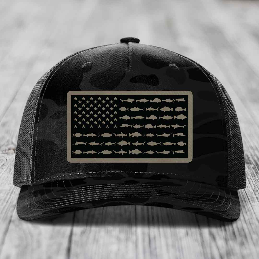 Black camouflage trucker hat with American flag patch made of saltwater fish silhouettes.