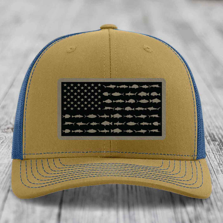 Tan and blue trucker hat with American flag patch featuring saltwater fish silhouettes instead of stars and stripes.