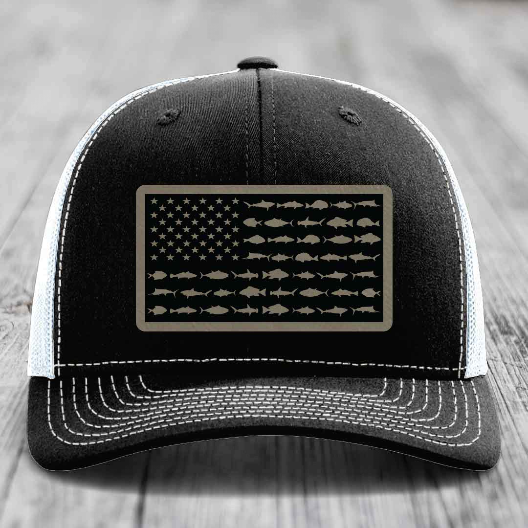 Black trucker hat with white stitching and a rectangular patch featuring an American flag design made of saltwater fish silhouettes.