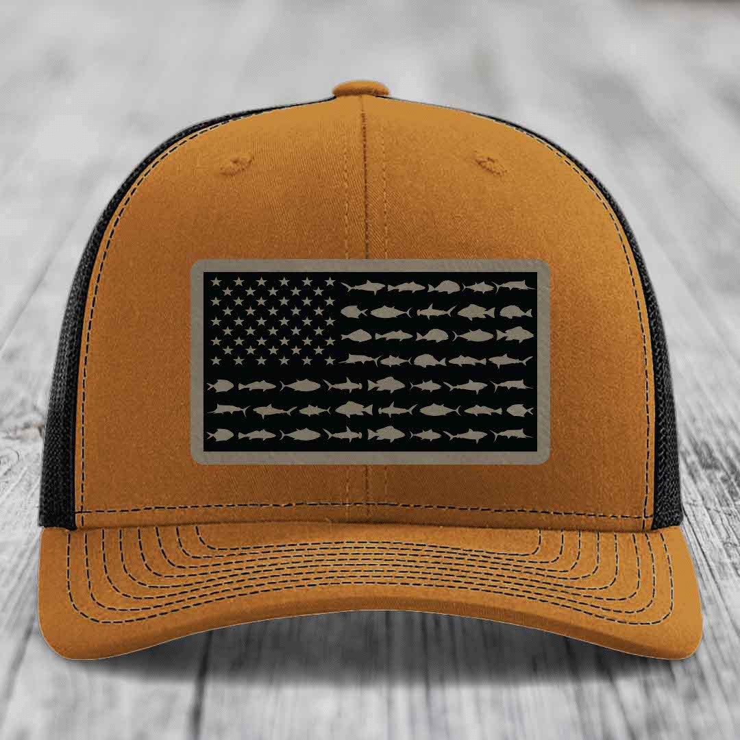 Tan trucker hat with black mesh back and American flag patch featuring fish silhouettes instead of stars and stripes.