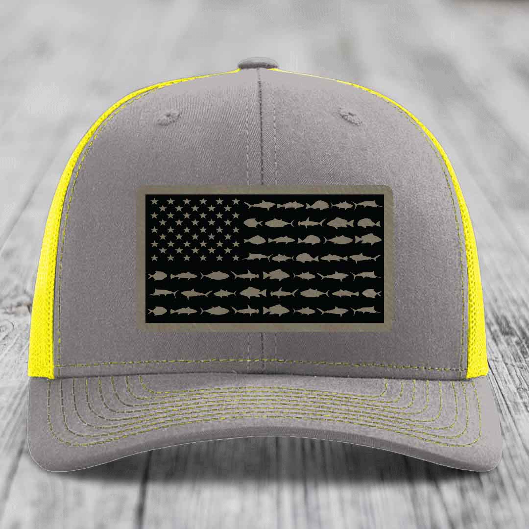 Grey trucker hat with yellow mesh and stitching, featuring a saltwater fish flag patch.