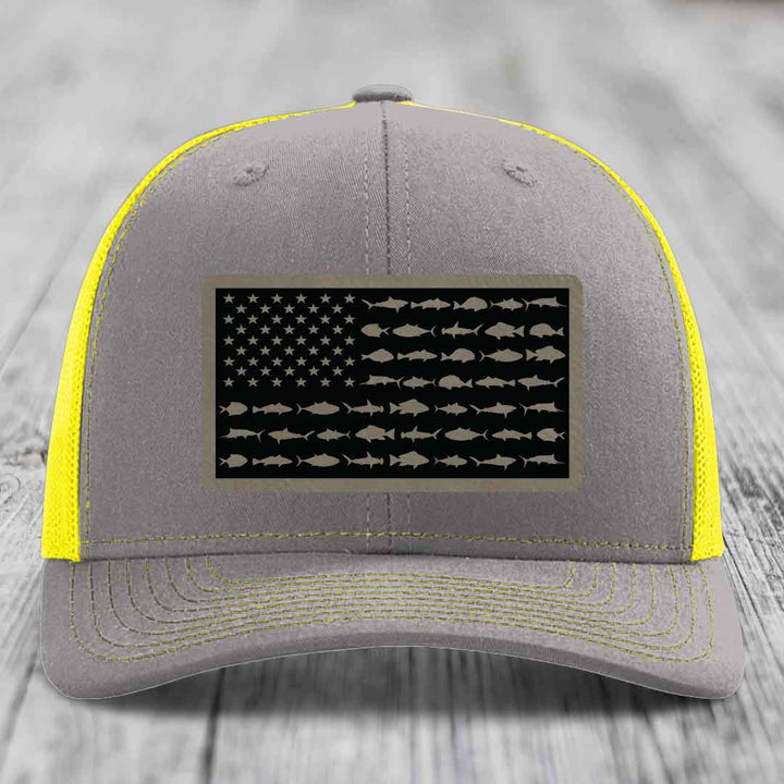 Grey trucker hat with yellow mesh and stitching, featuring a saltwater fish flag patch.