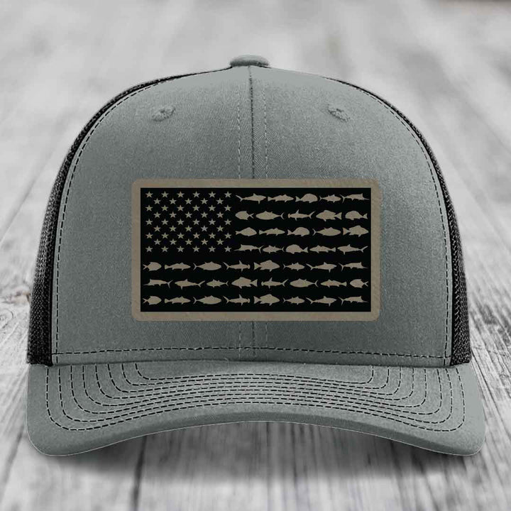 Grey trucker hat with black mesh back and a rectangular patch featuring an American flag design made of fish silhouettes.