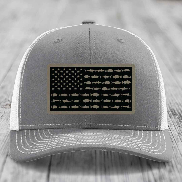 Grey trucker hat with white mesh back and stitched details, featuring a saltwater fish flag patch.