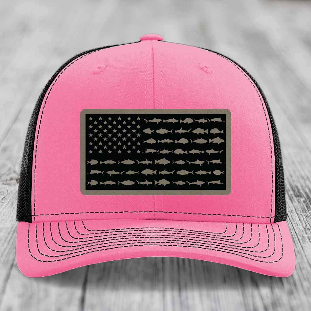 Pink trucker hat with black mesh back and a rectangular patch featuring an American flag design made of fish silhouettes.