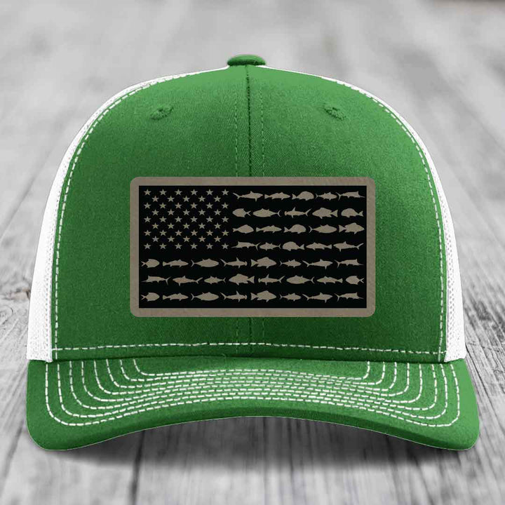 Green trucker hat with white mesh back and stitching, featuring a rectangular patch of an American flag made with fish silhouettes.