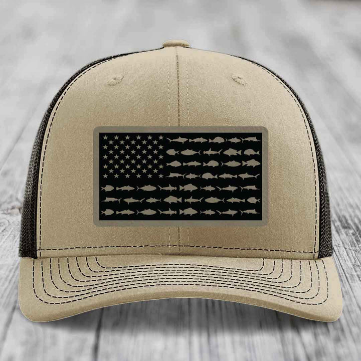 Beige trucker hat with black American flag patch featuring fish silhouettes instead of stars and stripes.