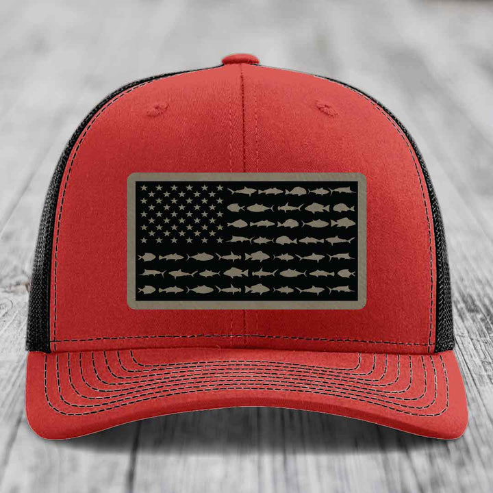 Red and black trucker hat with American flag patch featuring fish silhouettes instead of stars and stripes.