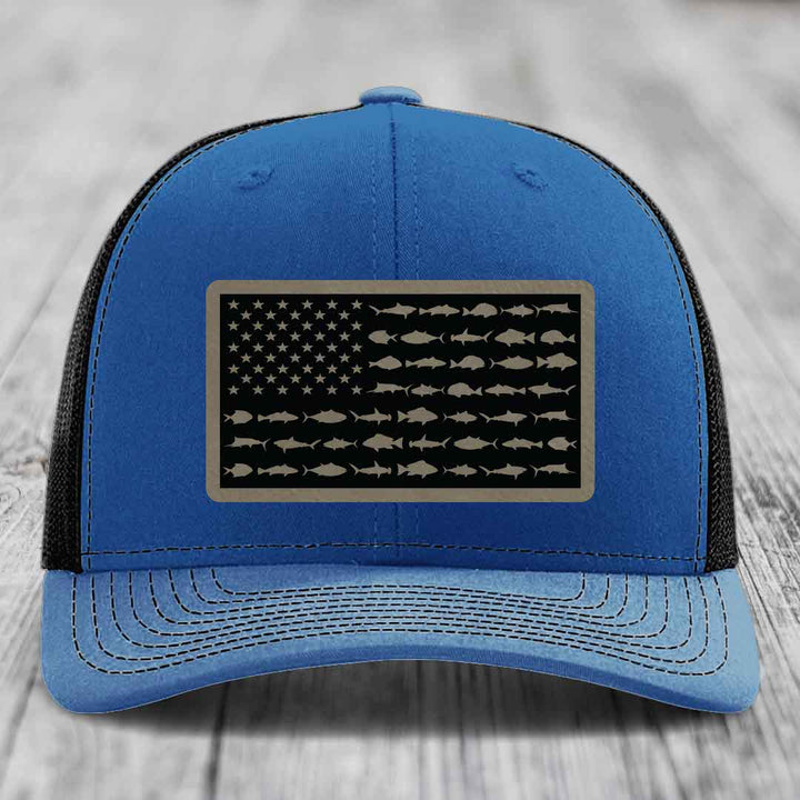 Blue trucker hat with black mesh back, featuring a rectangular patch of an American flag design made with fish silhouettes instead of stars and stripes.