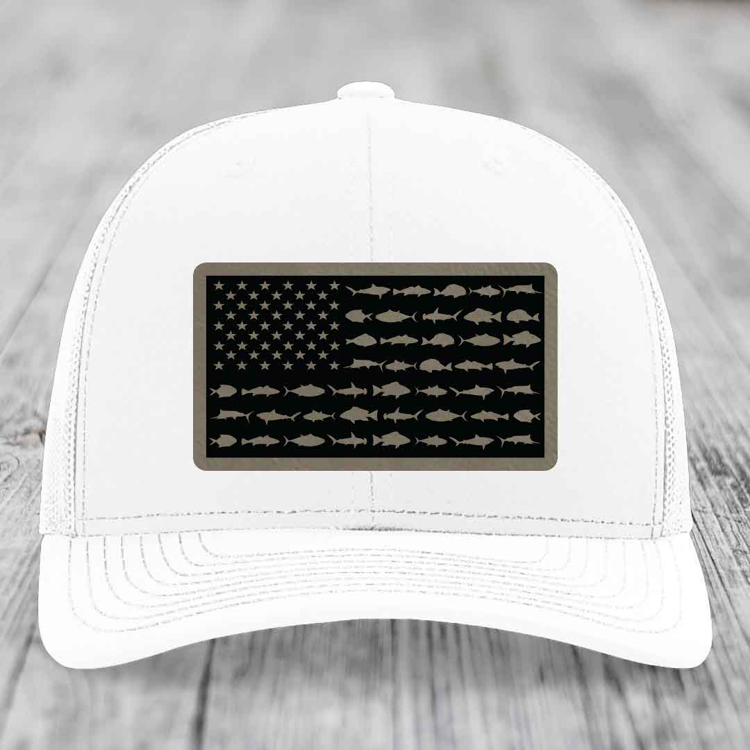 White trucker hat with a black leather patch featuring an American flag design made of fish silhouettes.