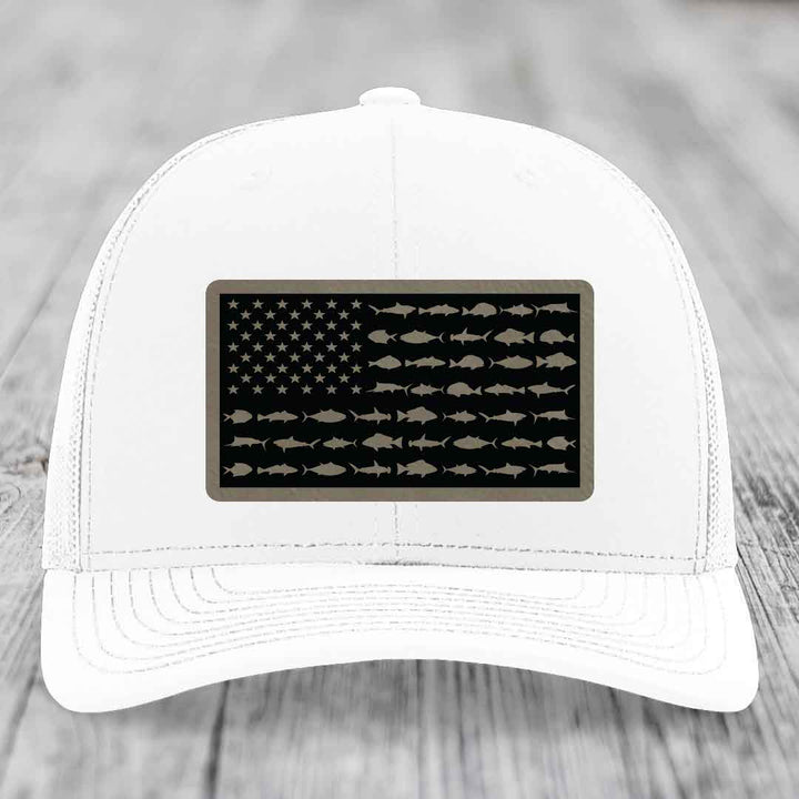 White trucker hat with a black leather patch featuring an American flag design made of fish silhouettes.