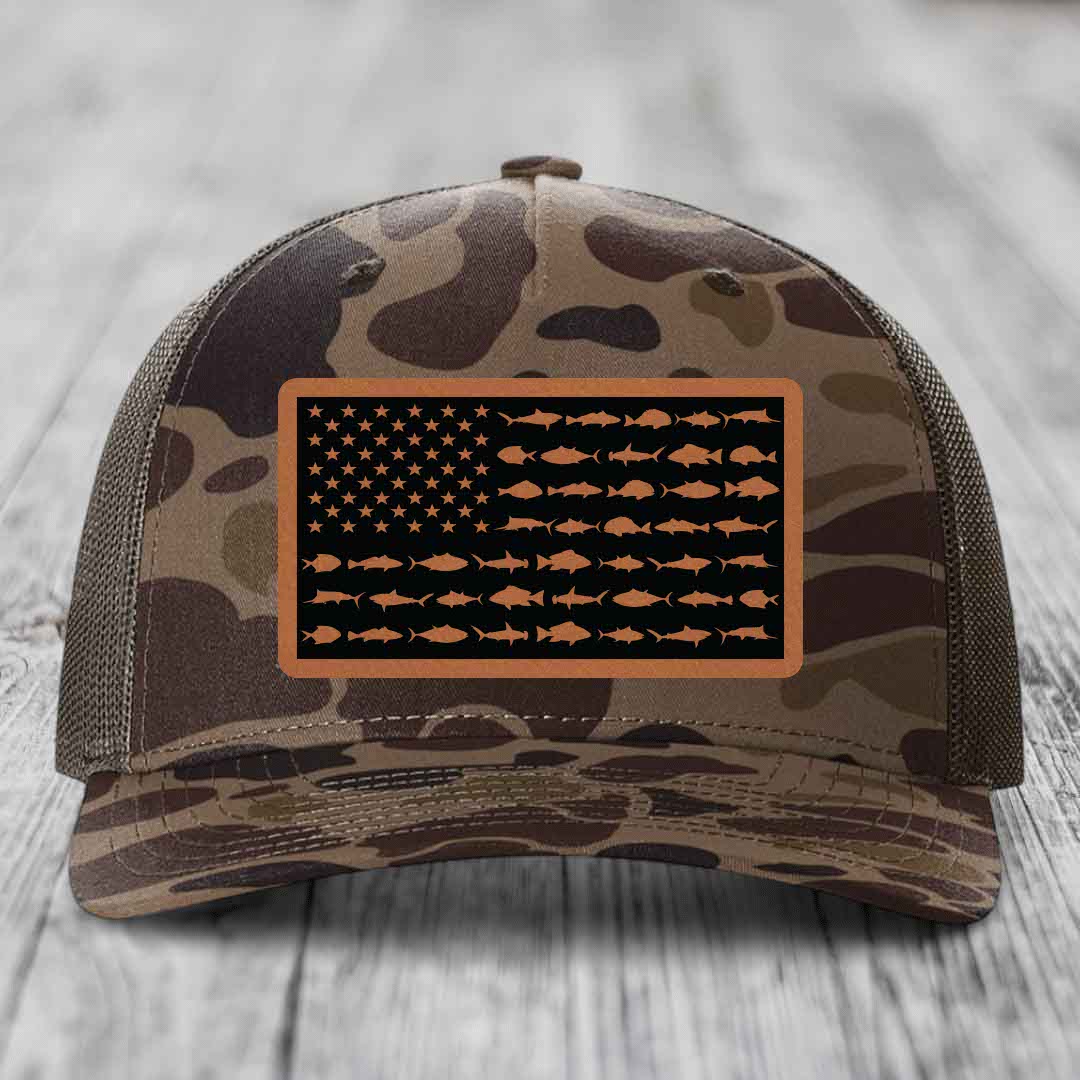 Camouflage trucker hat with American flag patch made of fish silhouettes on black background.