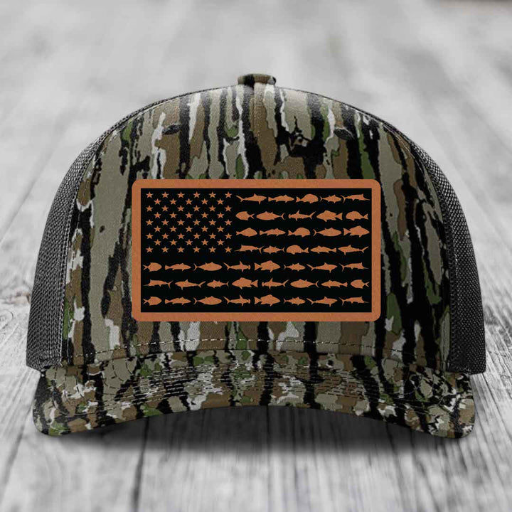 Camouflage trucker hat with American flag patch made of saltwater fish silhouettes in tan on black background.