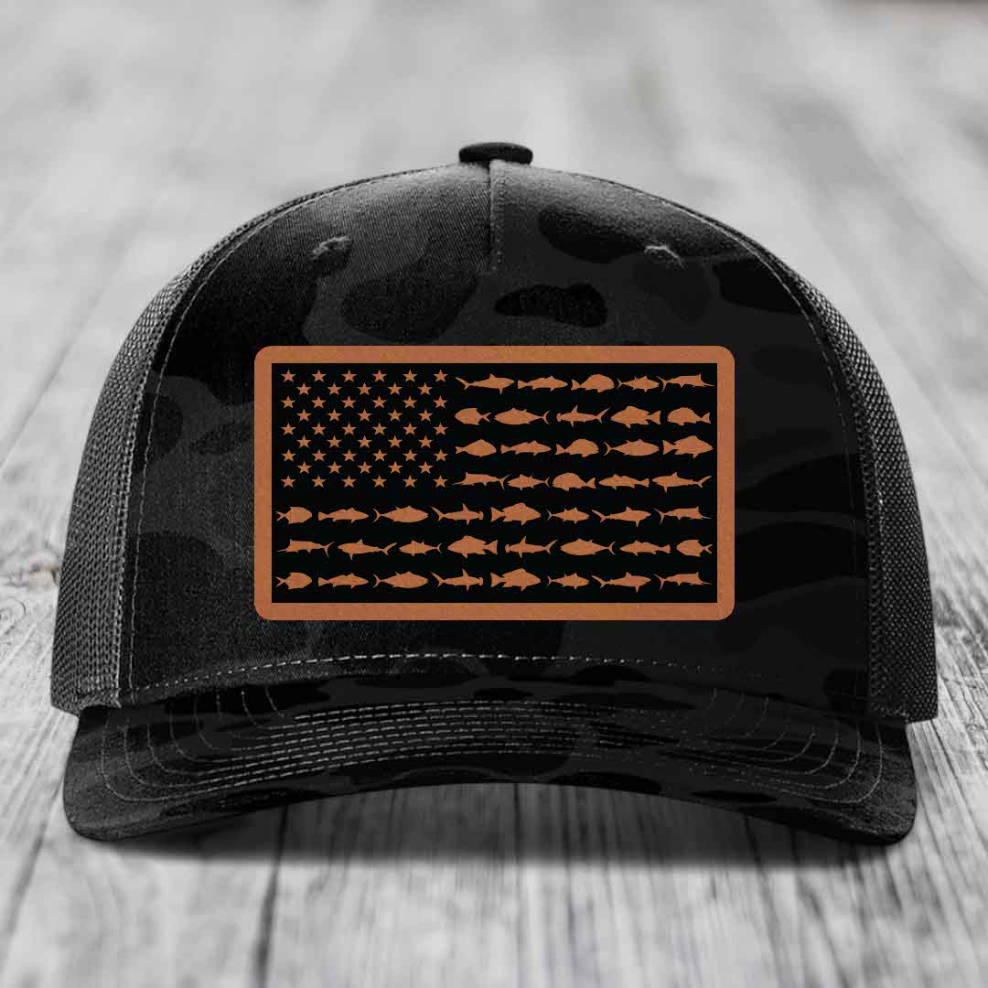 Black trucker hat with camouflage pattern and American flag patch made of saltwater fish silhouettes in brown leatherette.