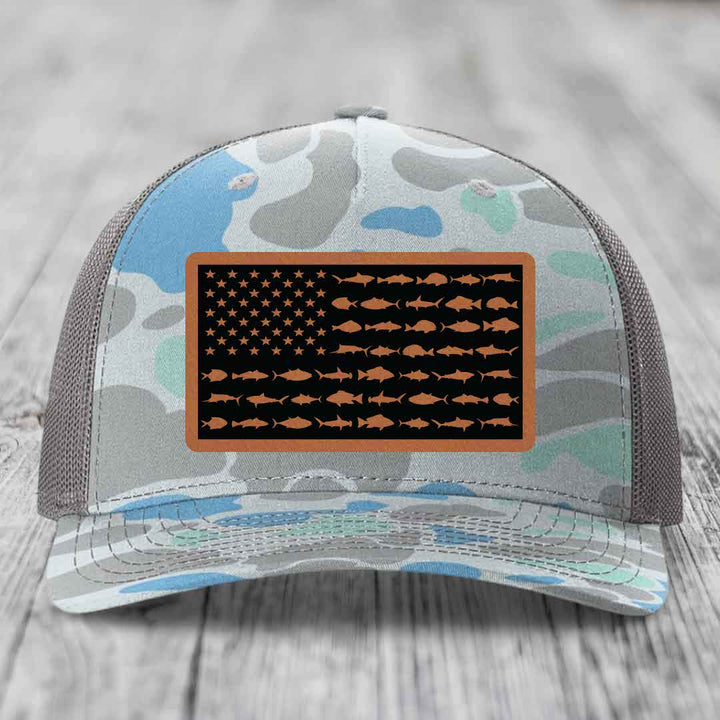 Camouflage trucker hat with American flag patch featuring fish silhouettes instead of stars and stripes.