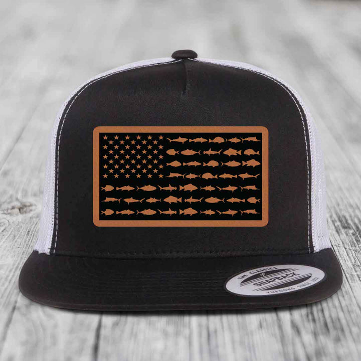 Black and white trucker hat with a brown leather patch featuring an American flag design made of fish silhouettes.