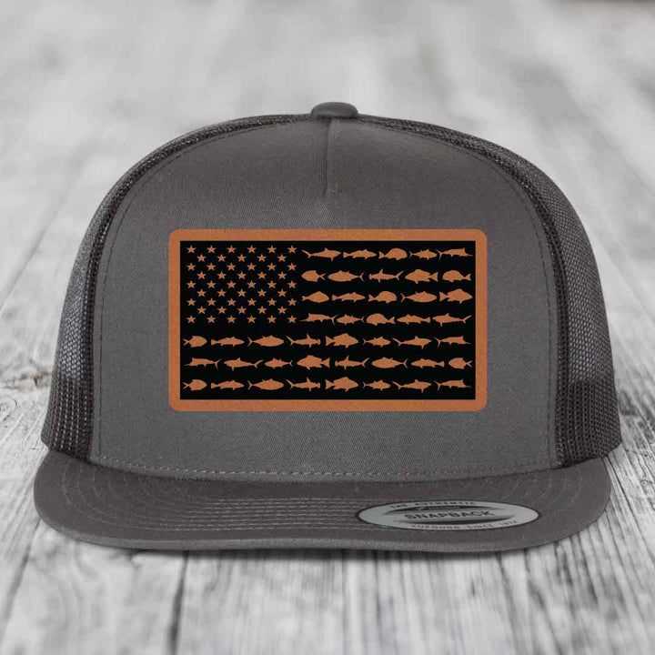 Grey trucker hat with a brown leather patch featuring an American flag design made of fish silhouettes.