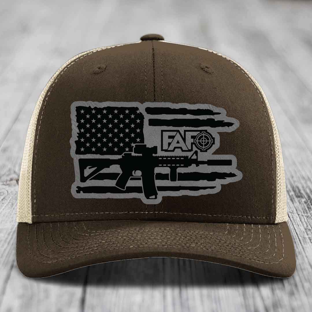 Brown trucker hat with American flag and AR-15 graphic patch on front.