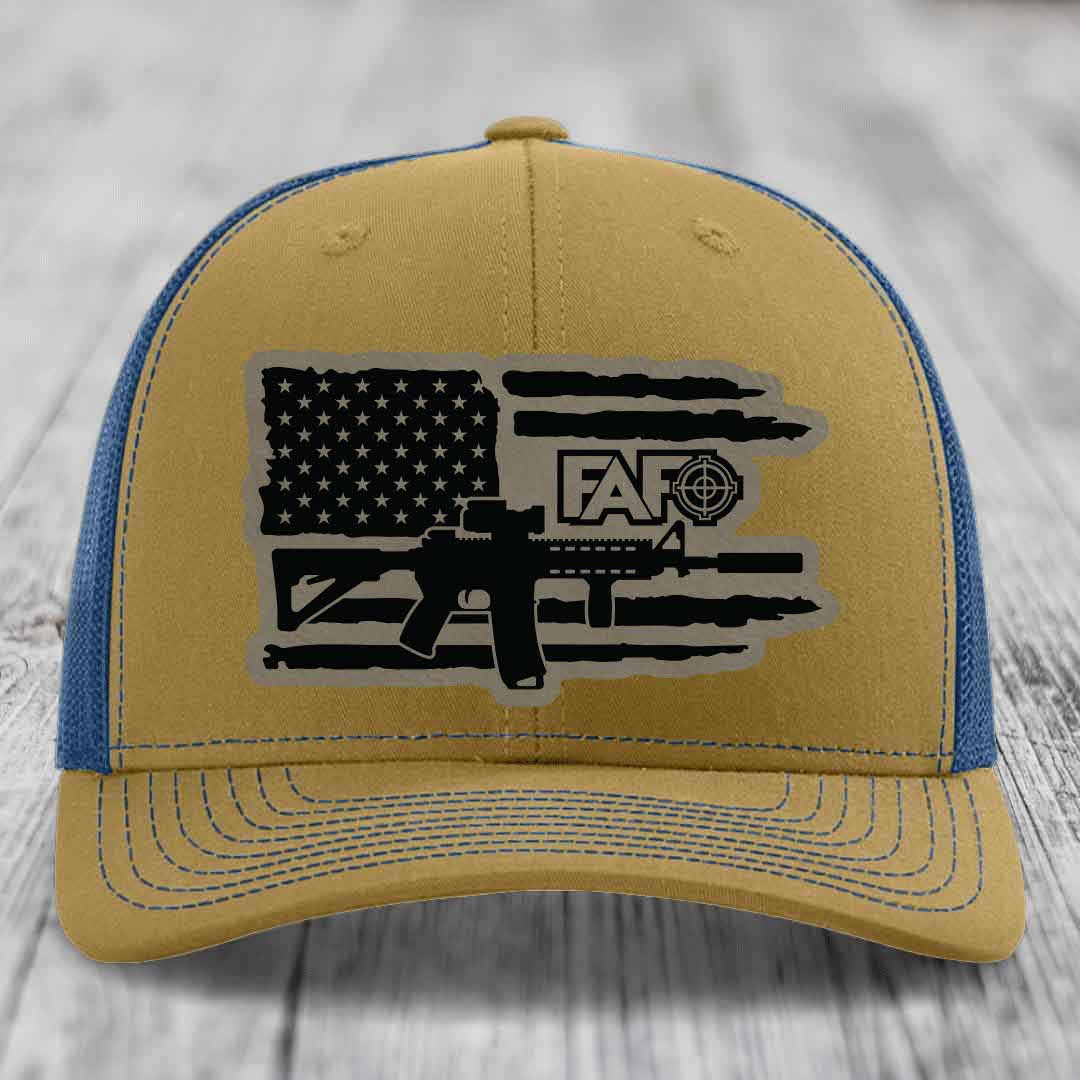 Tan and blue trucker hat with American flag and AR-15 graphic patch on front.