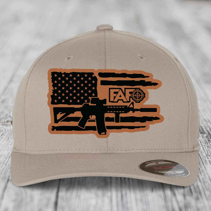 Tan baseball cap with American flag and AR-15 graphic patch on front.