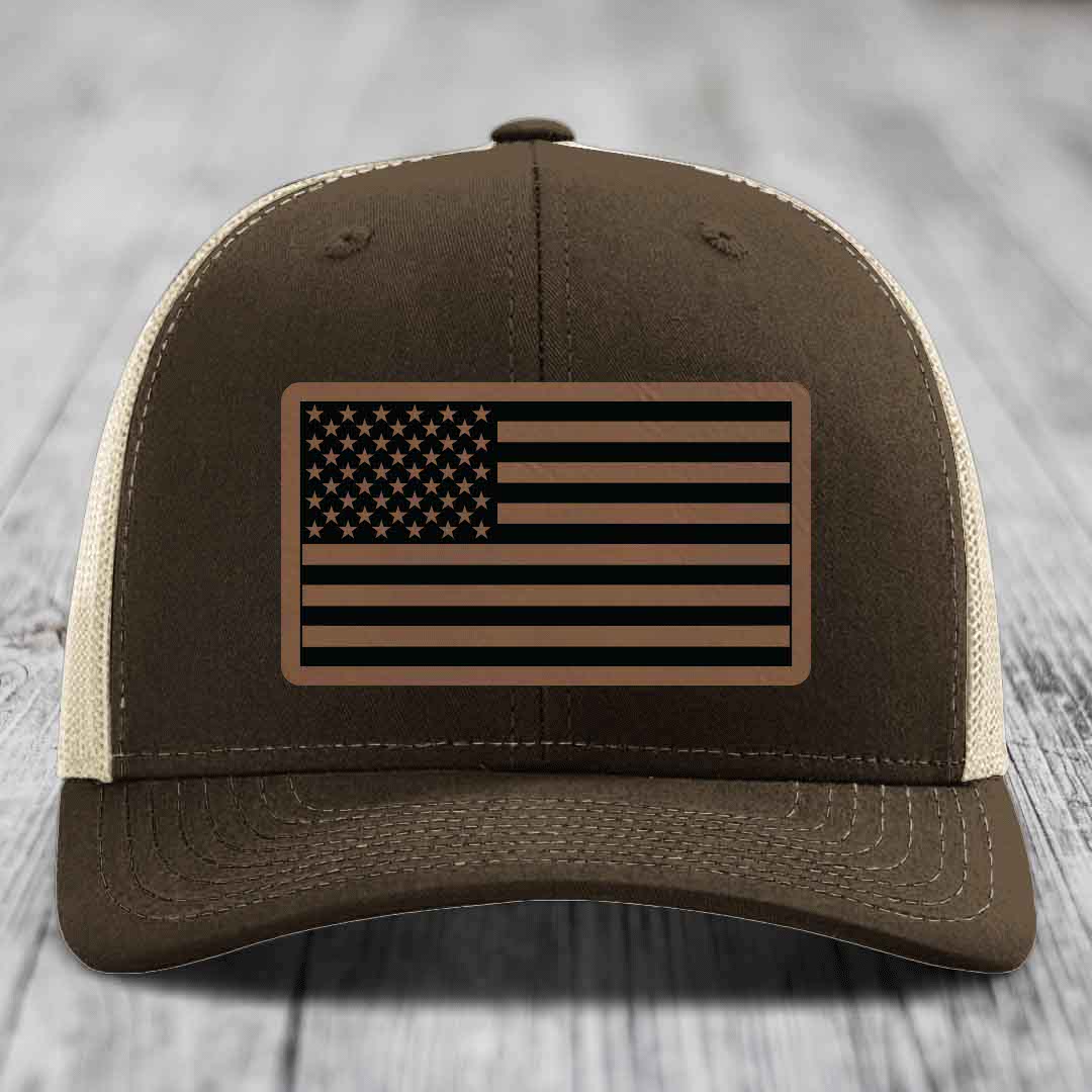 Brown trucker hat with beige mesh back and American flag leather patch on front.