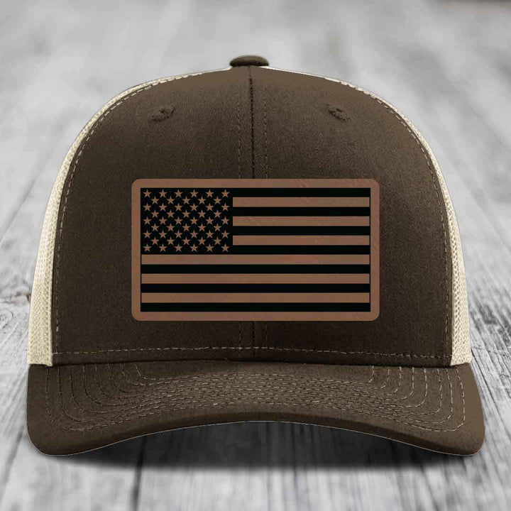 Brown trucker hat with beige mesh back and American flag leather patch on front.