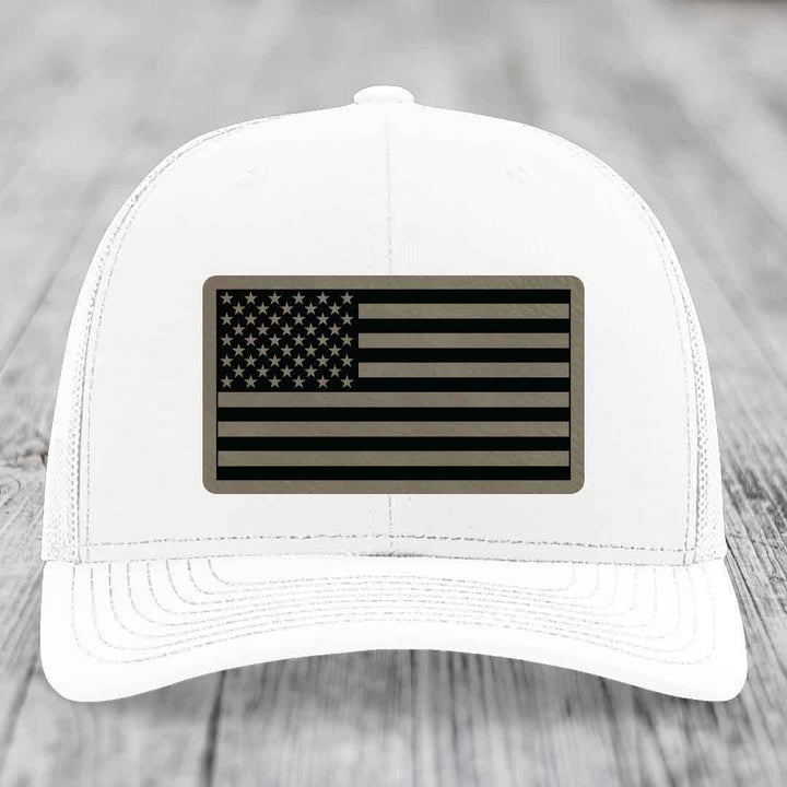 White trucker hat with American flag patch in black and tan leatherette.