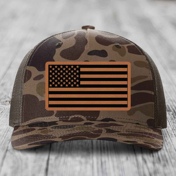 Camouflage trucker hat with American flag leather patch on front.