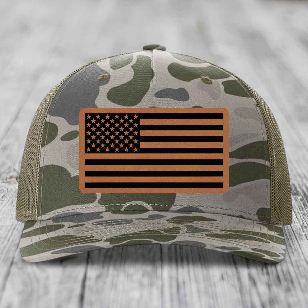 Camouflage trucker hat with American flag leather patch on front.