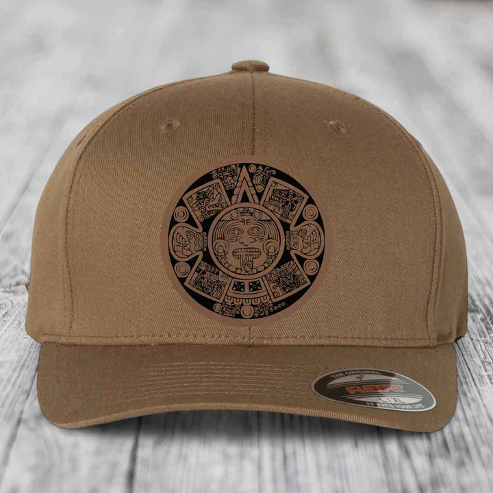 Tan baseball cap with Aztec calendar patch on front, featuring intricate black and tan design.