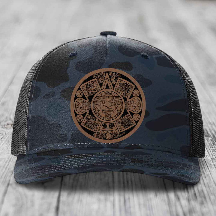 Camouflage trucker hat with Aztec calendar leather patch on front.