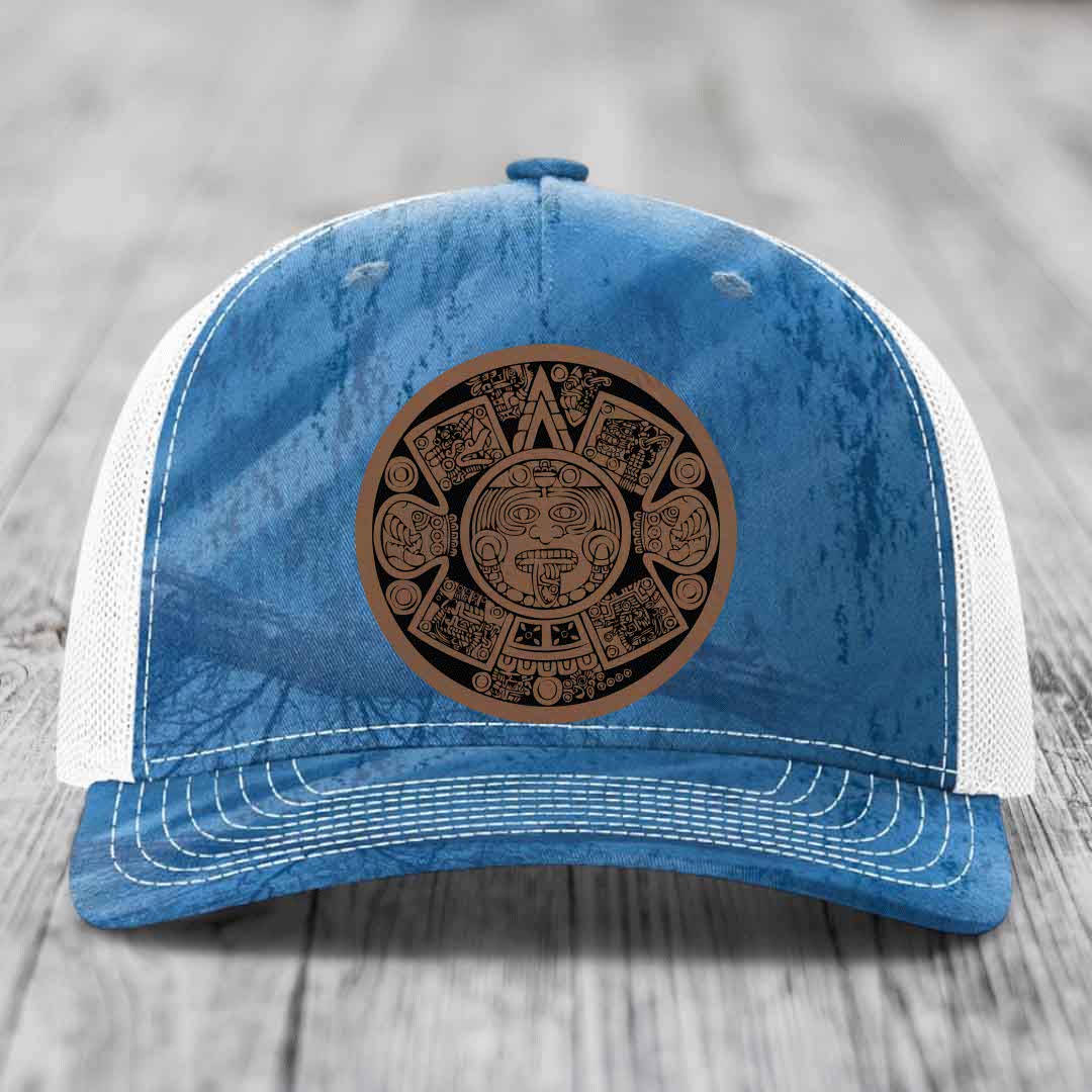Blue and white trucker hat with an Aztec calendar leather patch on the front.