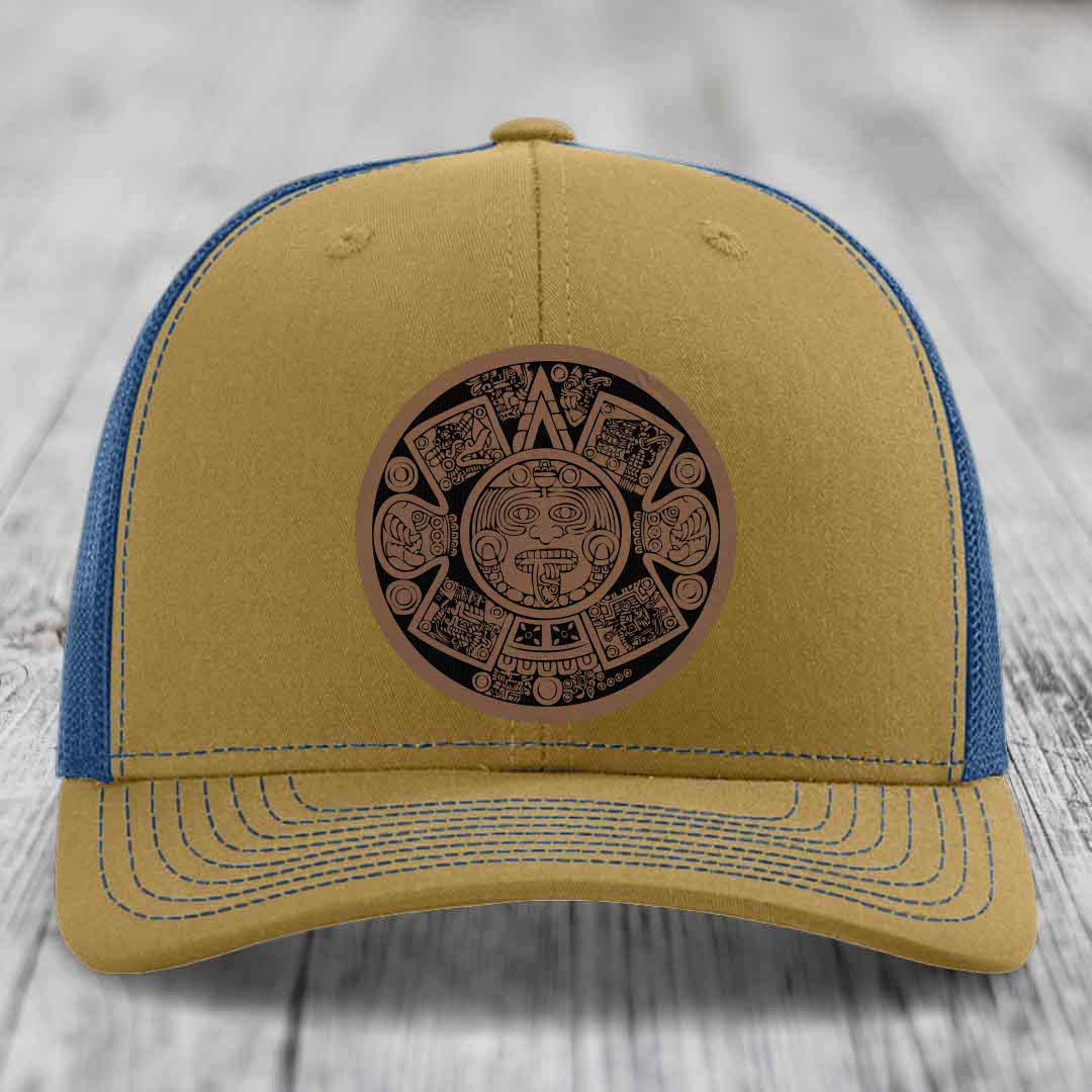 Tan trucker hat with blue mesh back and Aztec calendar leather patch on front.